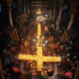 Brennendes Kreuz in mitten vor betenden Menschen in einer Kirche