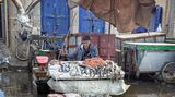 Mann sitzt vor Fischtheke im Regen
