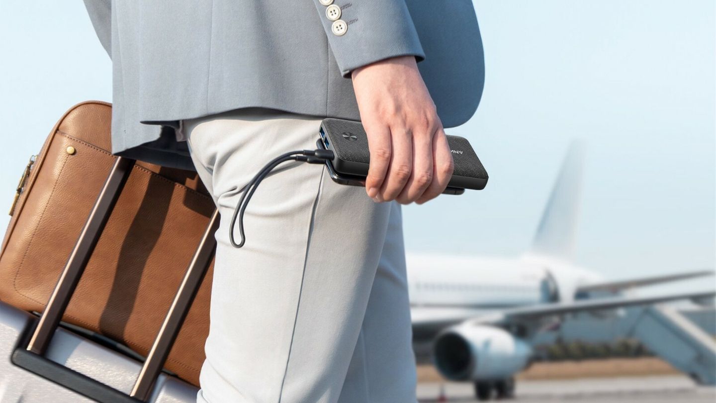 Ein Mann im Anzug geht über ein Rollfold, in der Hand hält er eine Powerbank
