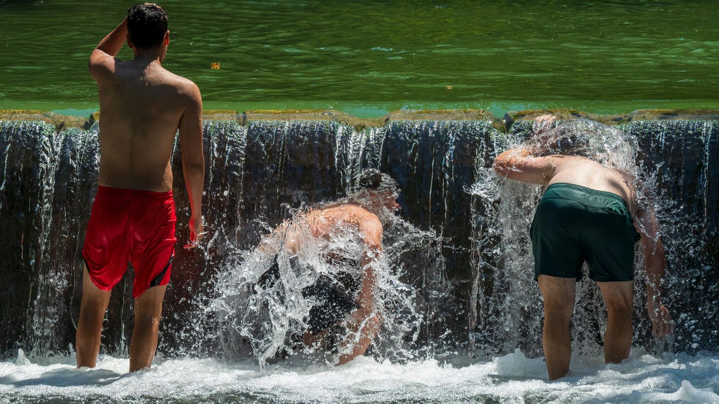 Jugendliche kühlen sich im Eisbach im Englischen Garten ab.