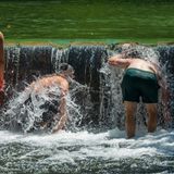 Jugendliche kühlen sich im Eisbach im Englischen Garten ab.