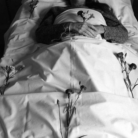 Körper in weiß gehüllt mit einer Rose in der Hand