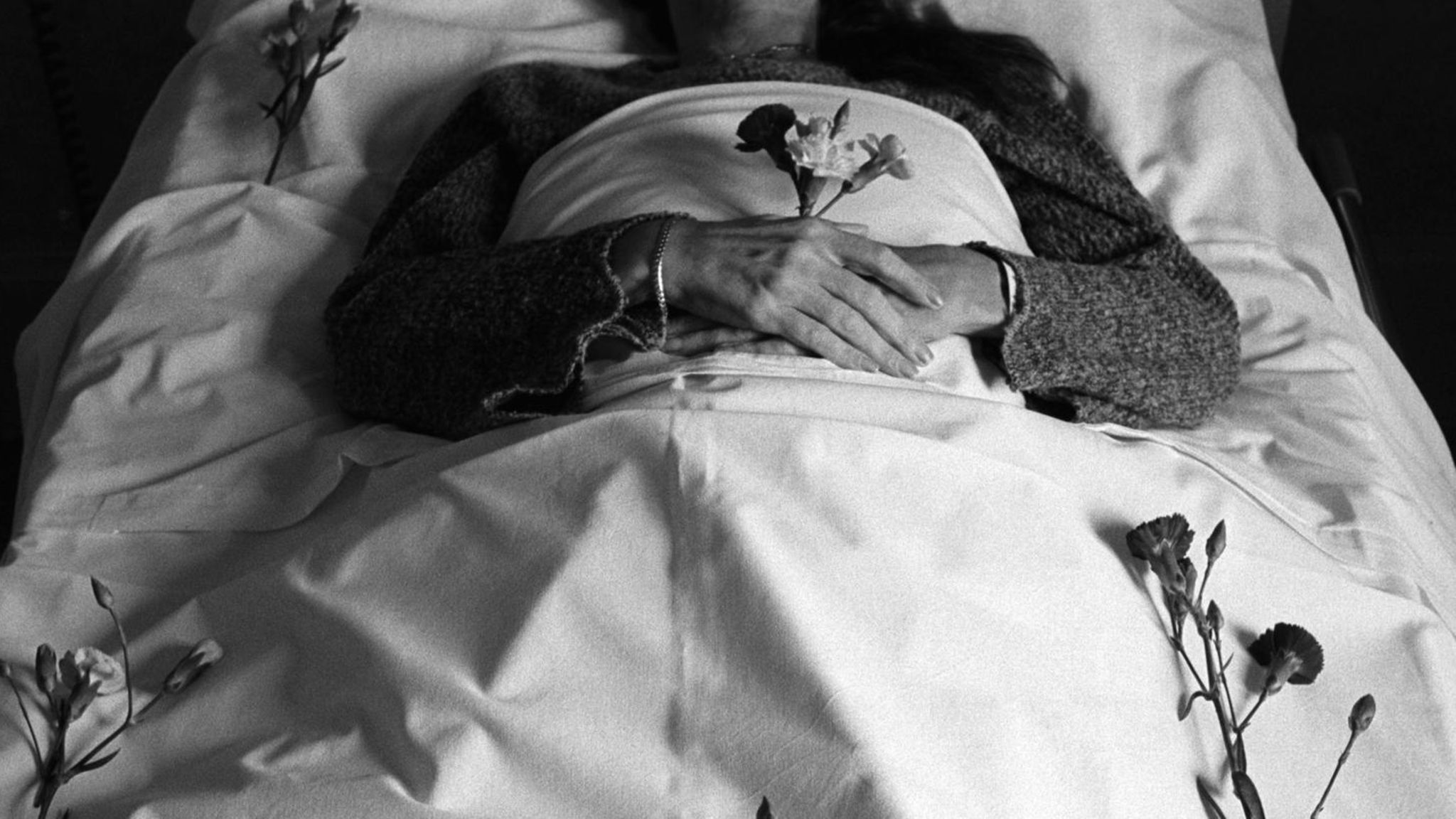 Körper in weiß gehüllt mit einer Rose in der Hand