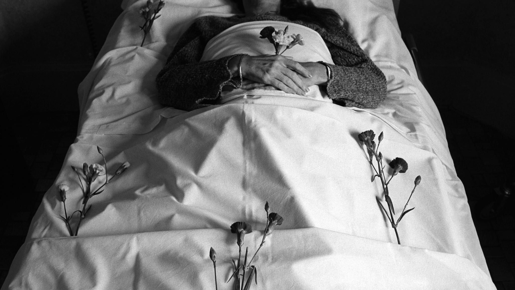 Körper in weiß gehüllt mit einer Rose in der Hand