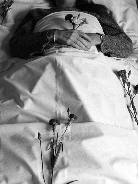 Körper in weiß gehüllt mit einer Rose in der Hand
