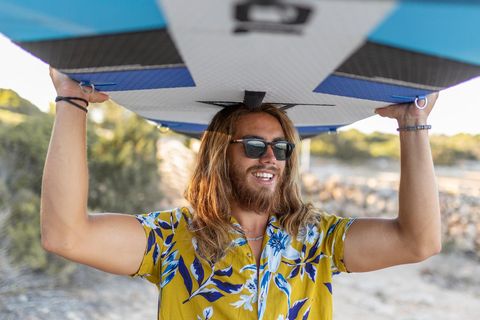 Surfer mit Sonnenbrille und Hawaiihemd am Strand
