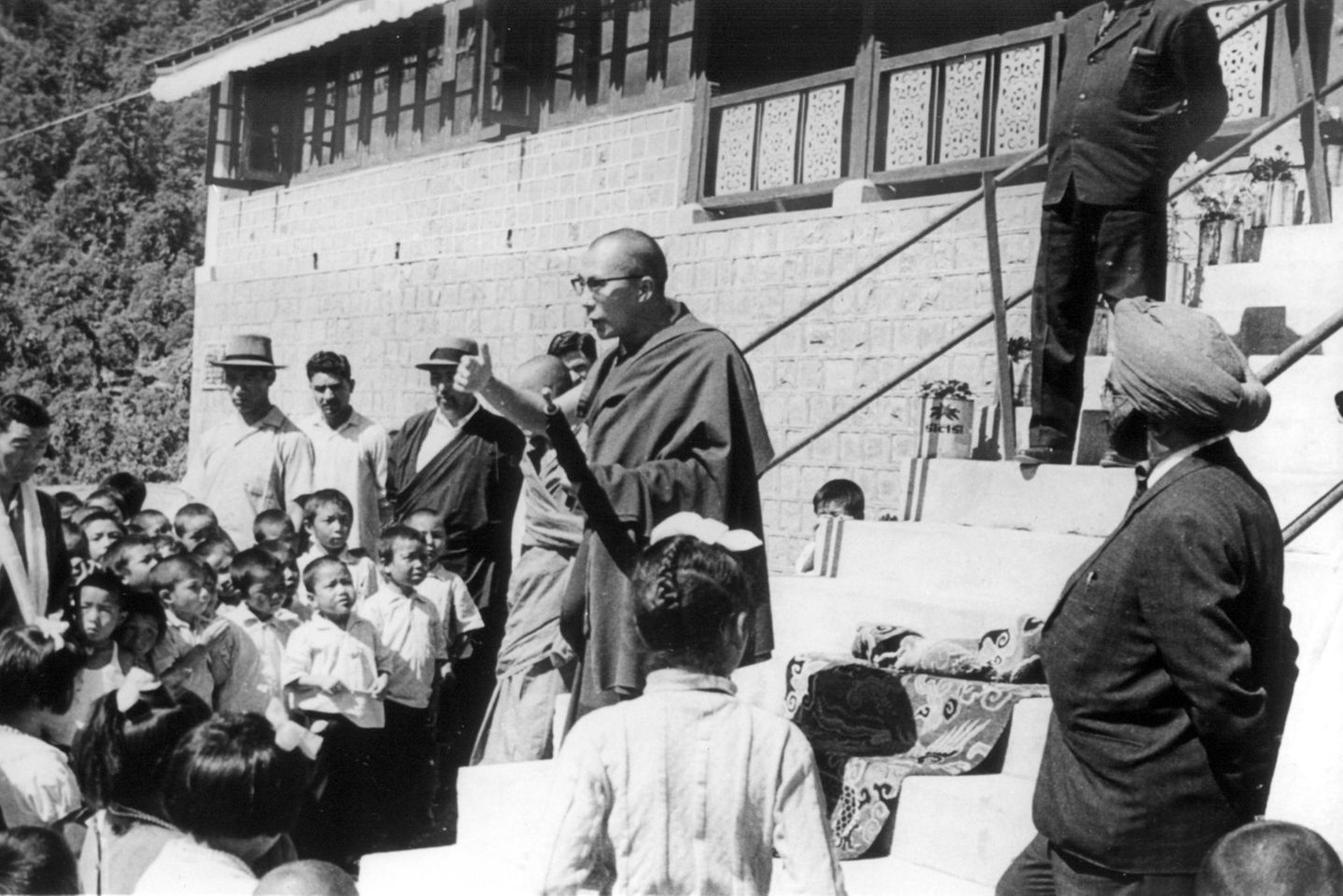 Der Dalai Lama steht vor Kindern und Erwachsenen und spricht Der Dalai Lama steht vor Kindern und Erwachsenen und spricht