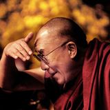 Der Dalai Lama blickt nach links und hält sich die Hand über die Augen