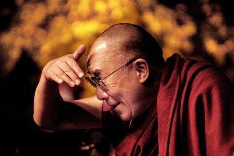 Der Dalai Lama blickt nach links und hält sich die Hand über die Augen