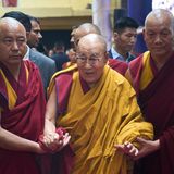 Der Dalai Lama wird von anderen Mönchen gestützt