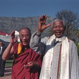 Der Dalai Lama und Nelson Mandela winken in die Kamera
