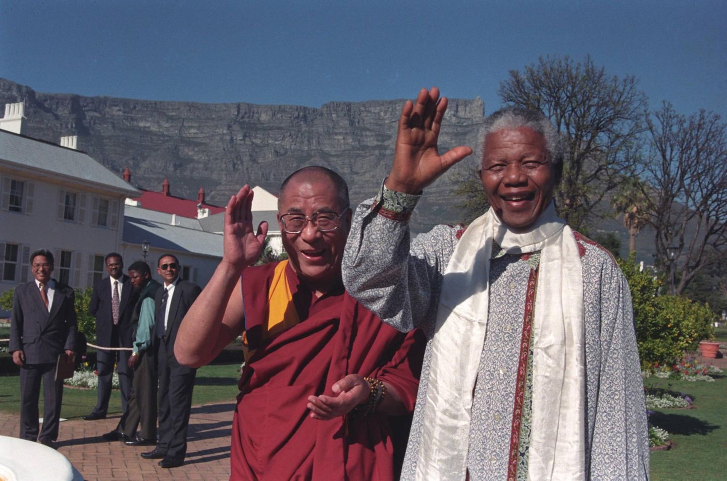 Der Dalai Lama und Nelson Mandela winken in die Kamera