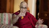 Der Dalai Lama lächelt und zeigt in die Kamera