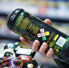 Ein Mann hält in einem Kiosk eine große Kartusche Lachgas in seiner rechten Hand