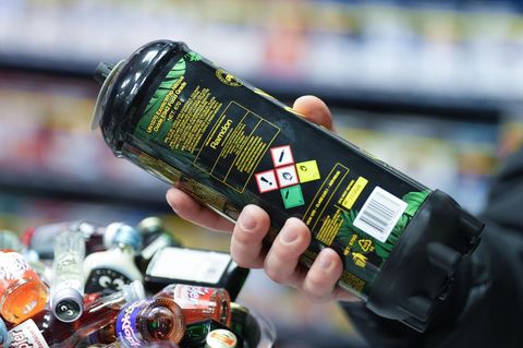 Ein Mann hält in einem Kiosk eine große Kartusche Lachgas in seiner rechten Hand