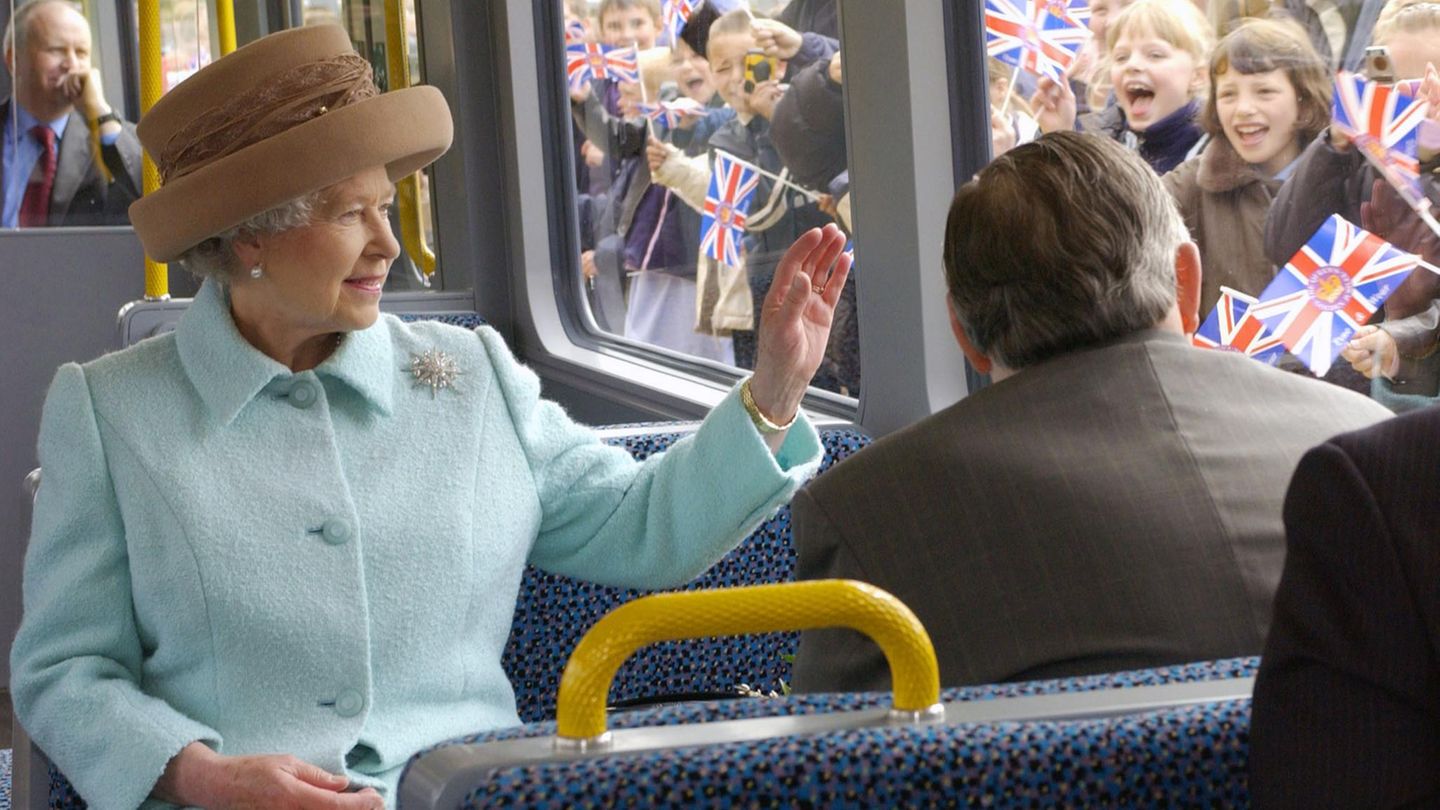 Die Queen sitzt in einem Zug und winkt nach draußen