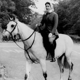 Die Queen sitzt auf ihrem Pferd, sie trägt ein Kopftuch und blickt nach vorn