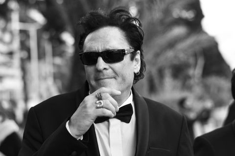 Madsen mit Sonnenbrille. Er hält sich eine Hand mit zwei dicken Ringen an das Kinn.