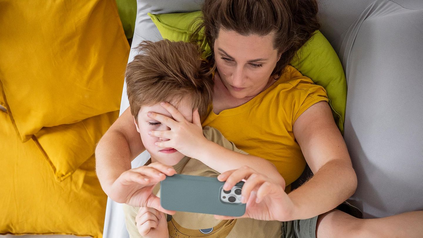 Mutter mit Kind auf dem Schoss, wie sie ein Seflie macht.