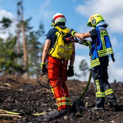 Mit Löschrucksäcken gehen die Feuerwehrleute etwa gegen Glutnester vor. Foto: Jacob Schröter/dpa