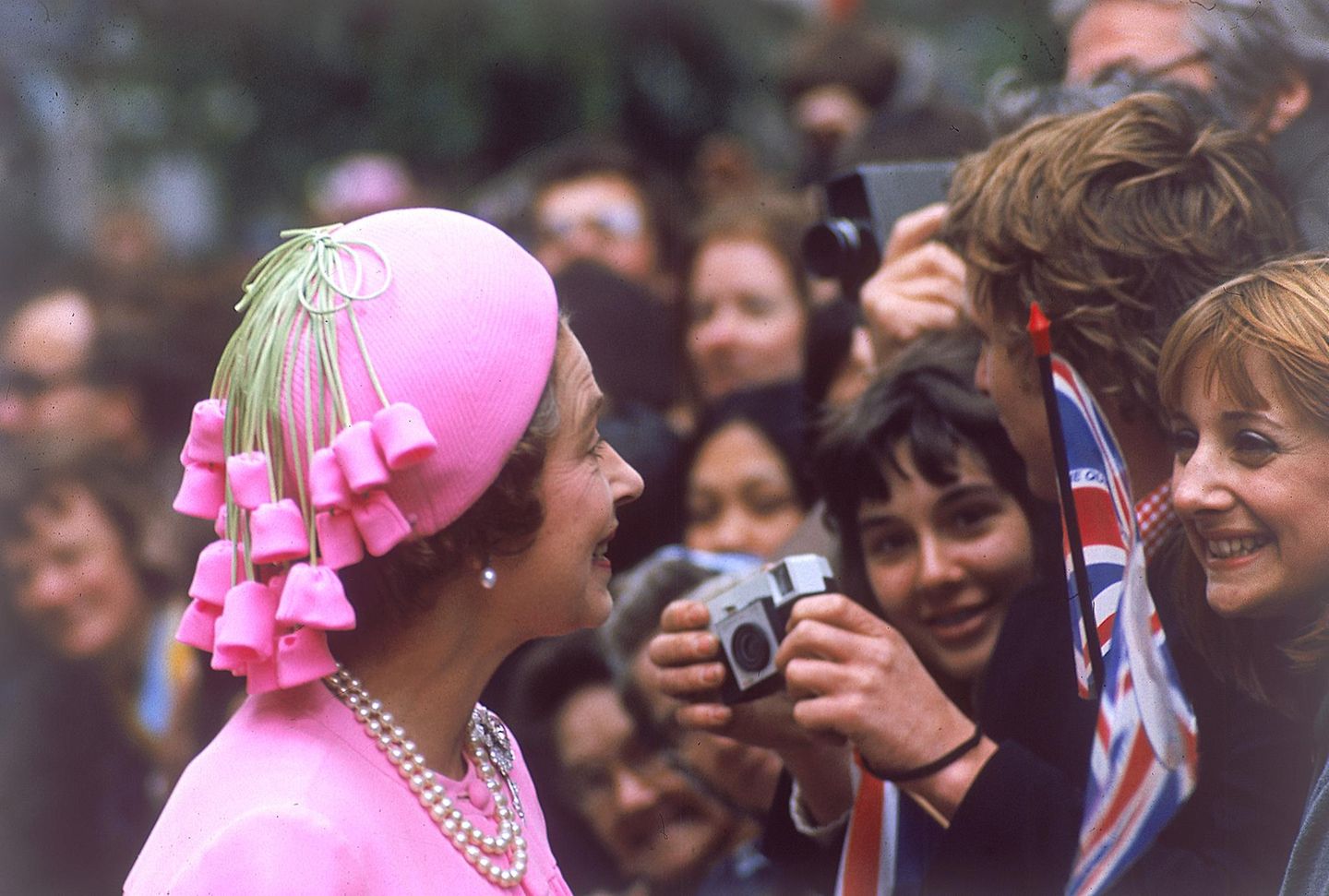 Die Queen 1977 mit pinkfarbenem Hut, an dem Bommeln hängen
