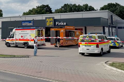 Zwei Rettungswagen und ein Polizeiauto stehen vor einem Supermarkt im Emsland, Niedersachsen
