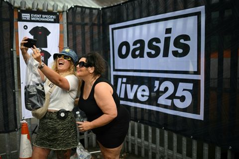 Oasis-Fans vor einem Tourplakat