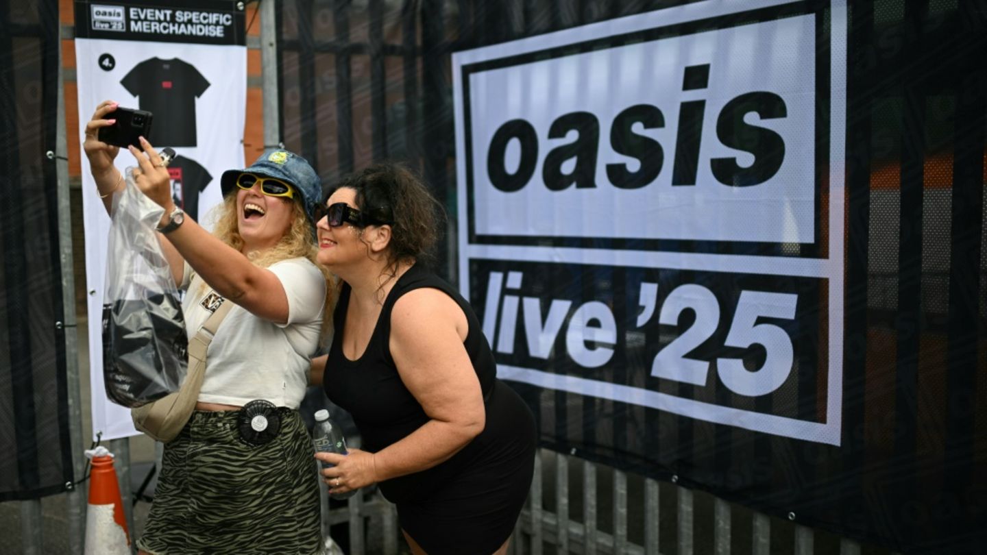 Oasis-Fans vor einem Tourplakat