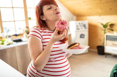 Schwangerschaft: eine schwangere Frau isst einen Donut