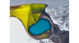 Das Blau eines Kratersees in grünen Berghängen