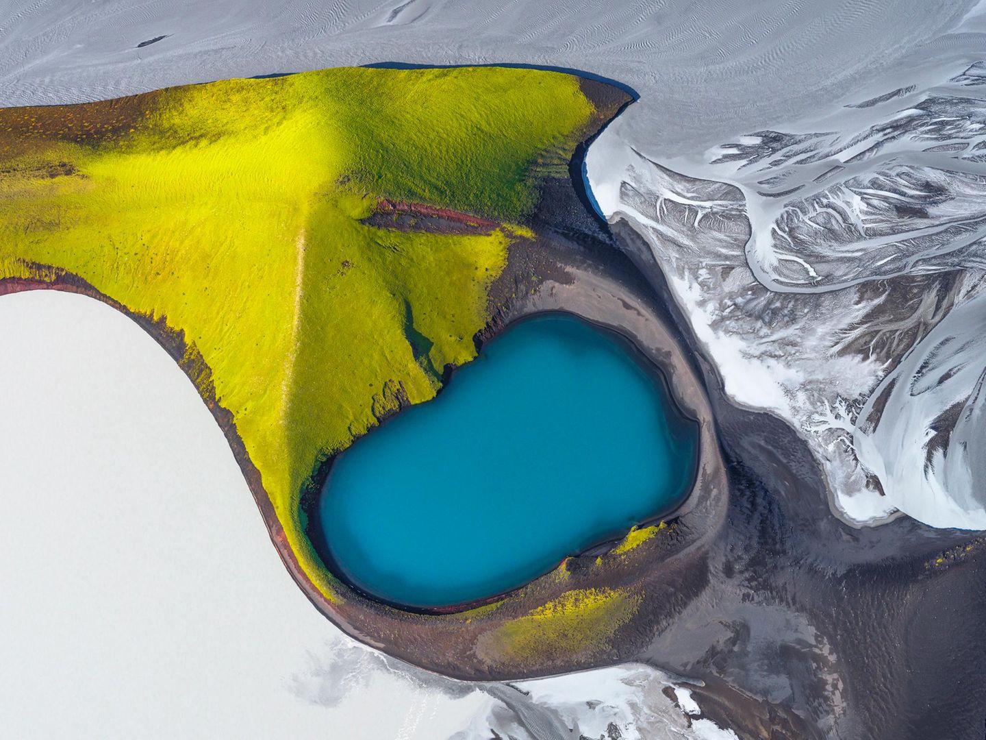 Das Blau eines Kratersees in grünen Berghängen