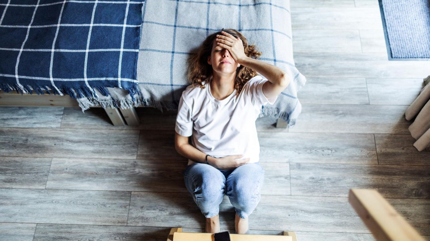 Frau mit Migräne liegt am Bett