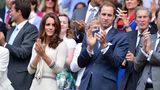 Kate klatscht auf der Tribüne, sie trägt ein eierschalenfarbenes Kleid