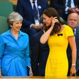 Kate im knallgelben Kleid von Dolce und Gabbana, sie streicht sich durch das braune Haar