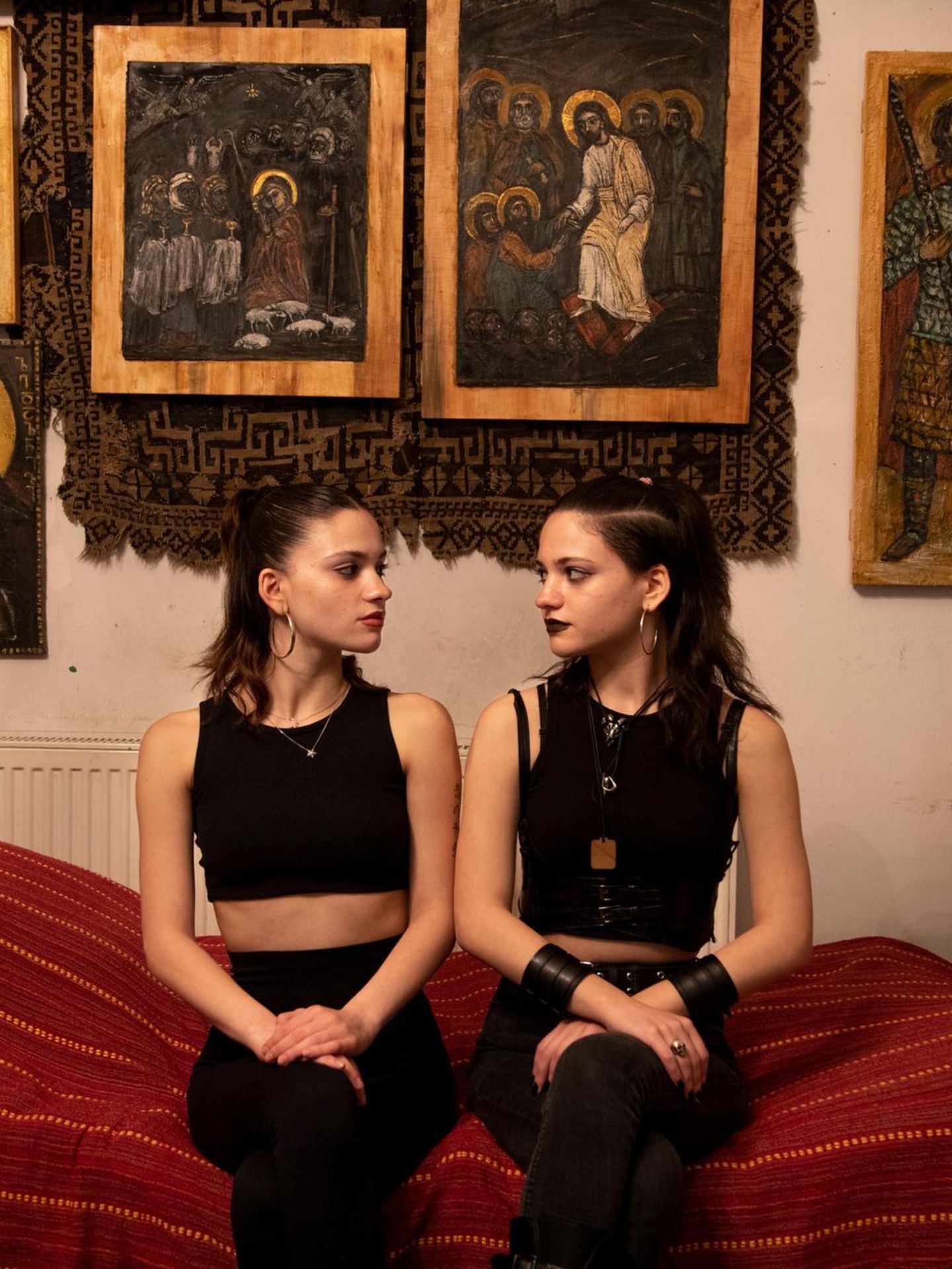 Ano und Tako sitzen auf einem Bett mit einer roten Tagesdecke