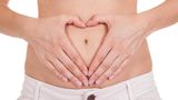 Körper: Bauch und Darm – Frau formt Herz mit den Fingern auf dem Bauch