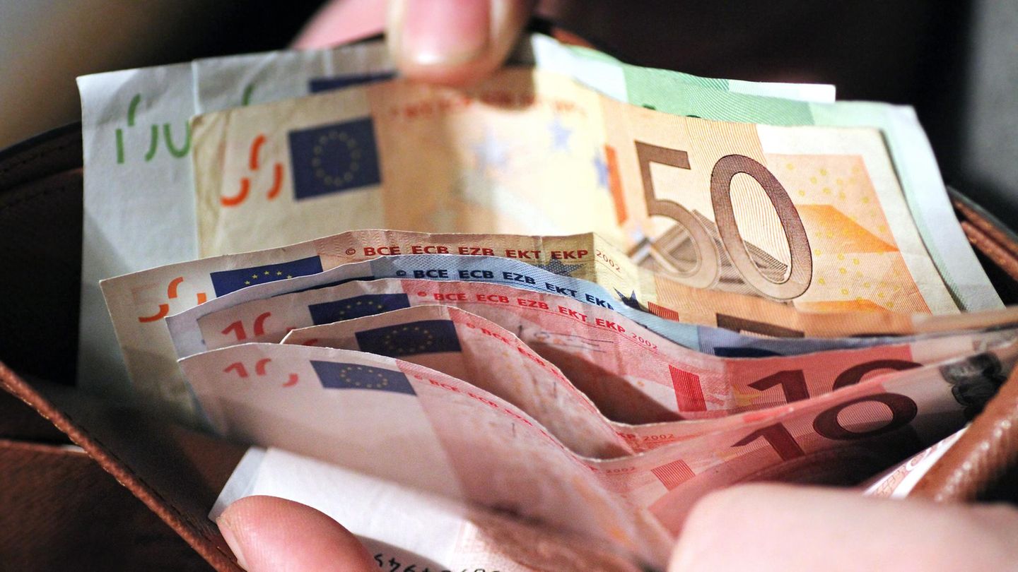 Eine Hand hält ein Portmonee auf, darin sind mehrere Hundert Euro Bargeld