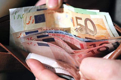 Eine Hand hält ein Portmonee auf, darin sind mehrere Hundert Euro Bargeld