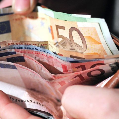 Eine Hand hält ein Portmonee auf, darin sind mehrere Hundert Euro Bargeld