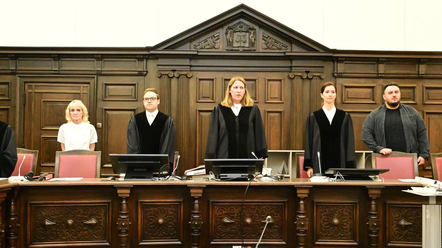 Zwei Frauen und ein Mann in schwarzen Roben stehen hinter der Richterbank im Block-Prozess, eingerahmt von