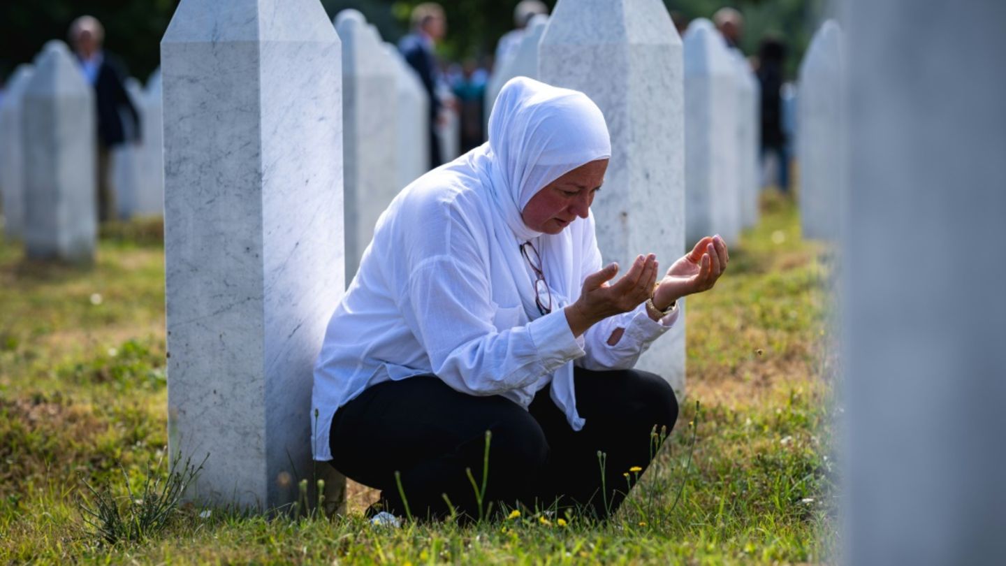 Frau betet zwischen Gräbern in der Nähe von Srebrenica