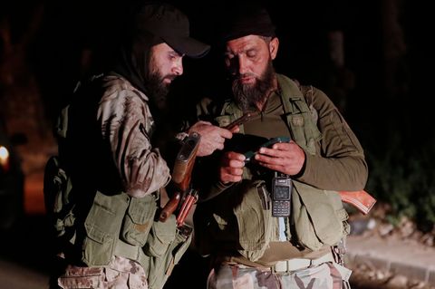 Sicherheitskräfte überprüfen ihre Mobiltelefone an einem Kontrollpunkt. In Syrien ist es wieder zu einem Gewaltausbruch gekommen