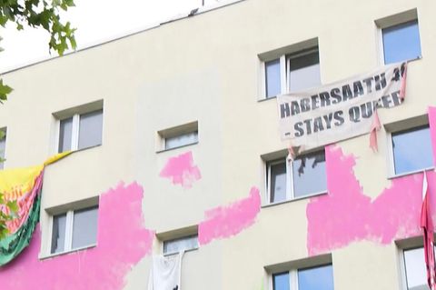 Wohnblock in Berlin Mitte, mit pinker Farbe besprayt und Flaggen und Bannern die draußen hängen