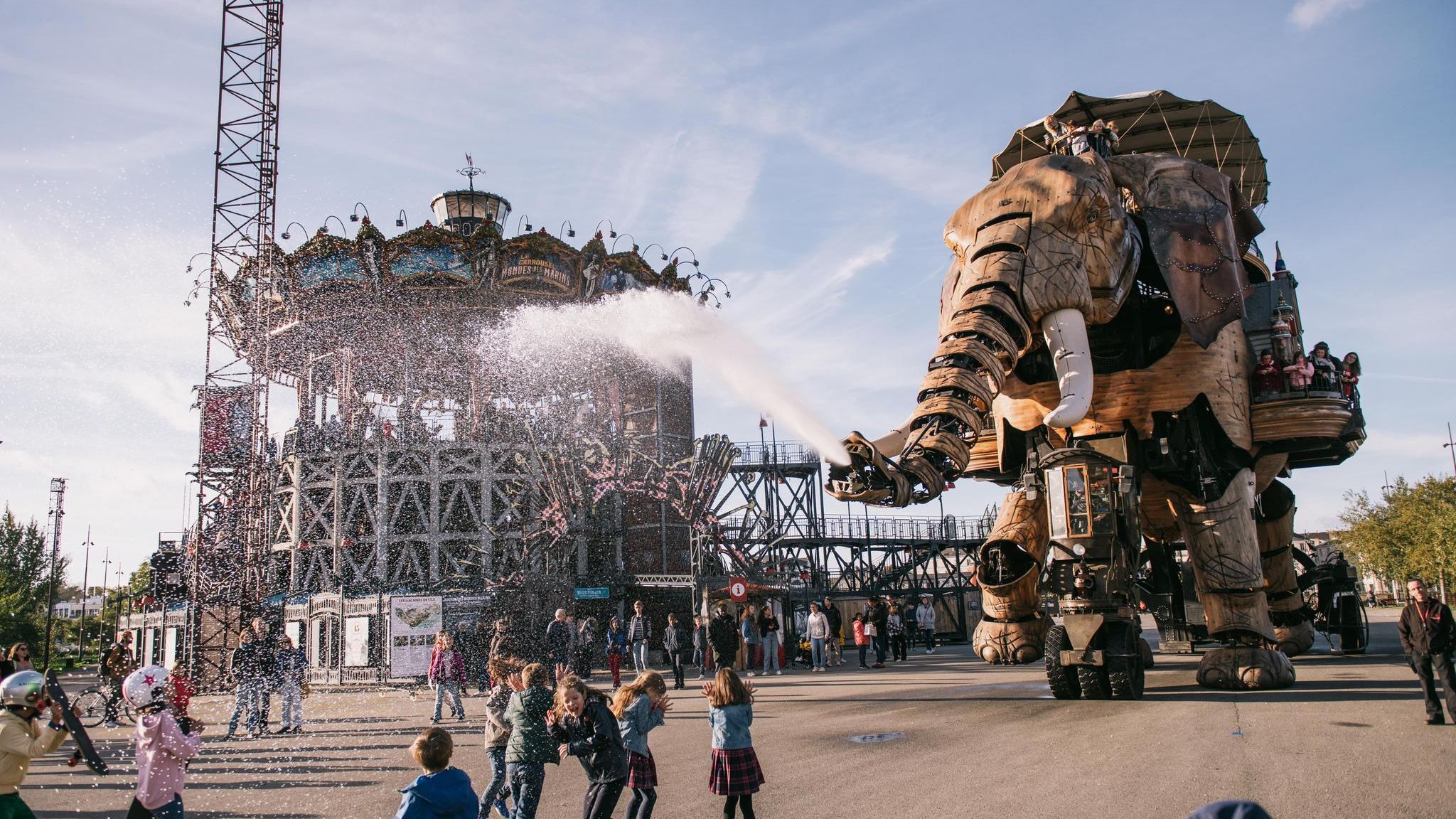 Ein großer Holzelefant srpüht Wasser auf die Besucher des Freizeit-Parks in Nantes