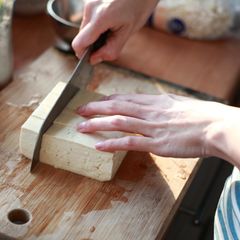 cutting Tofu on the chopping board in Kitchen