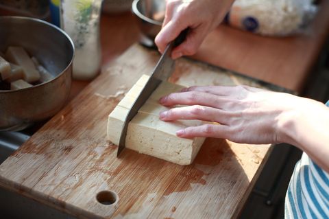 cutting Tofu on the chopping board in Kitchen