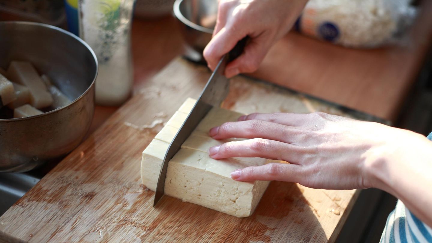 cutting Tofu on the chopping board in Kitchen
