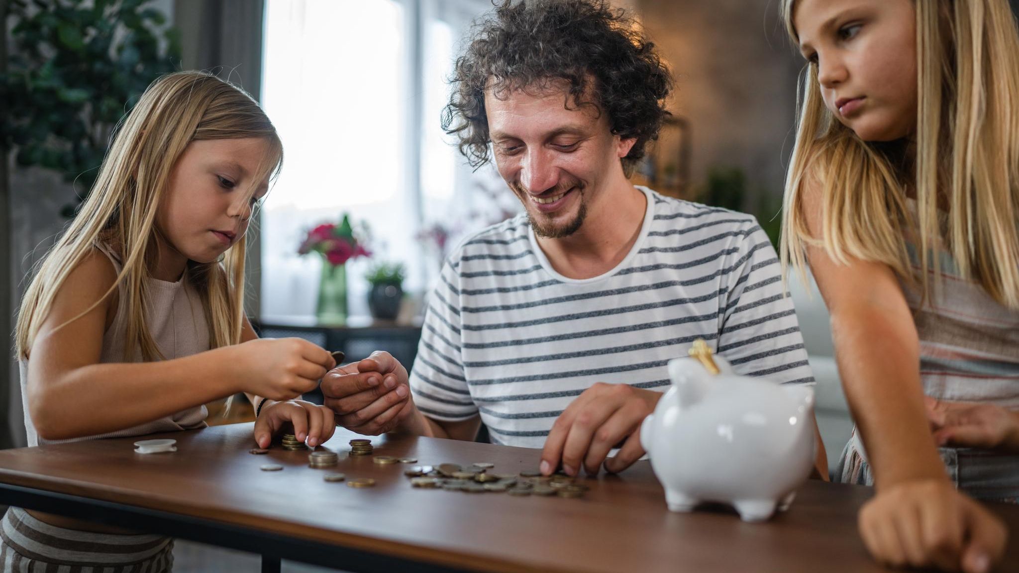 Sparen mit den Kindern: Vater sortiert Geld mit Töchtern