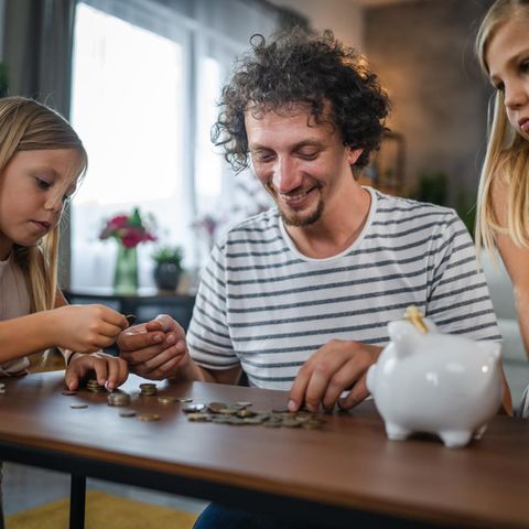 Sparen mit den Kindern: Vater sortiert Geld mit Töchtern