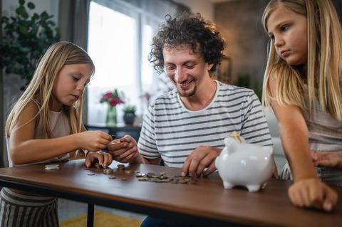 Sparen mit den Kindern: Vater sortiert Geld mit Töchtern
